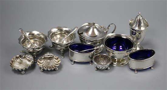 A silver three piece condiment set, three pairs of silver condiments, one other condiment and four spoons.